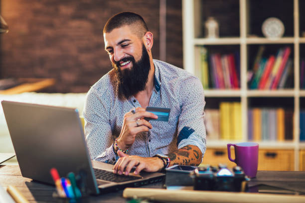 istock Young man working in home office using credit card for online payment 1336051265