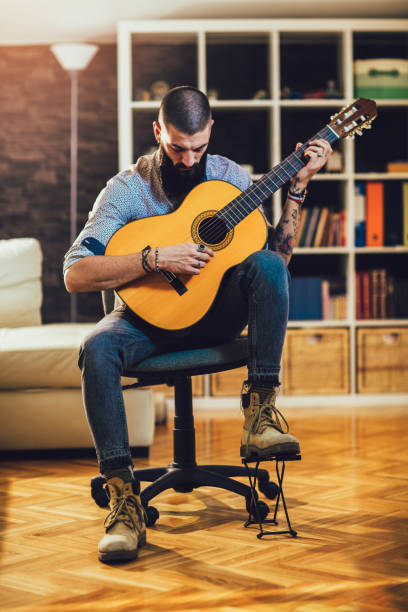 istock Handsome young bearded man playing classical guitar at home. 1336051324