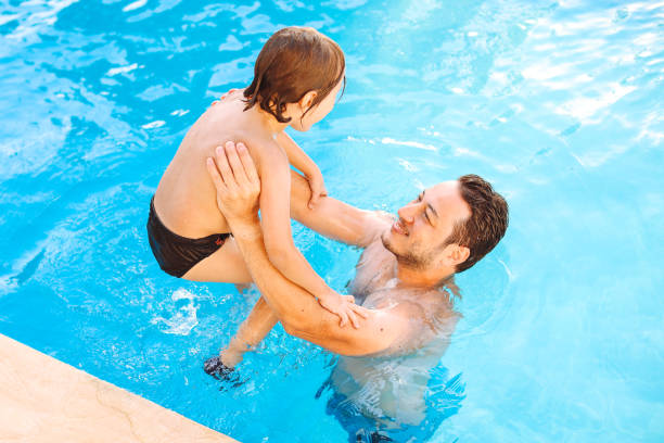 istock Cute little boy having fun with parents in pool 1336051563