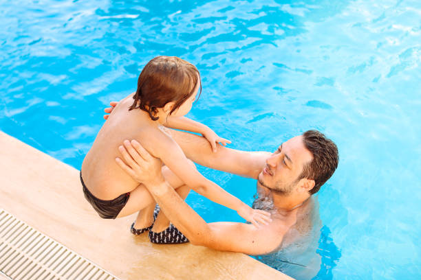 istock Cute little boy having fun with parents in pool 1336051640