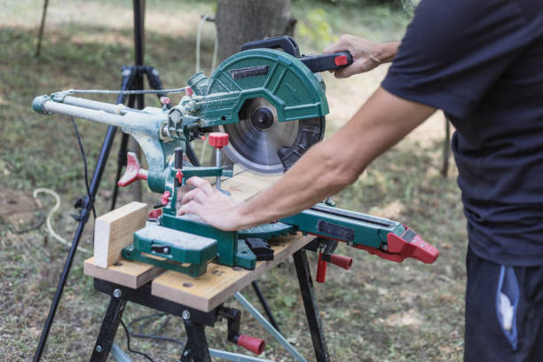 DIY Woodworking, cutting timber using miter saw Carpenter making slow cross cut on wood plank using miter saw, close-up miter saw stock pictures, royalty-free photos & images