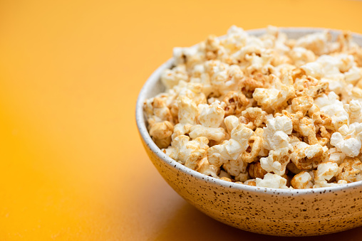 Popcorn in bowl on yellow background isolated. Closeup view, copy space