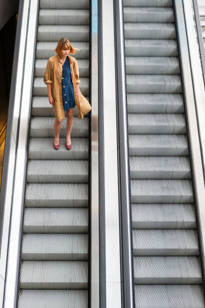 istock Trendy woman riding alone on a descending escalator 1336056917