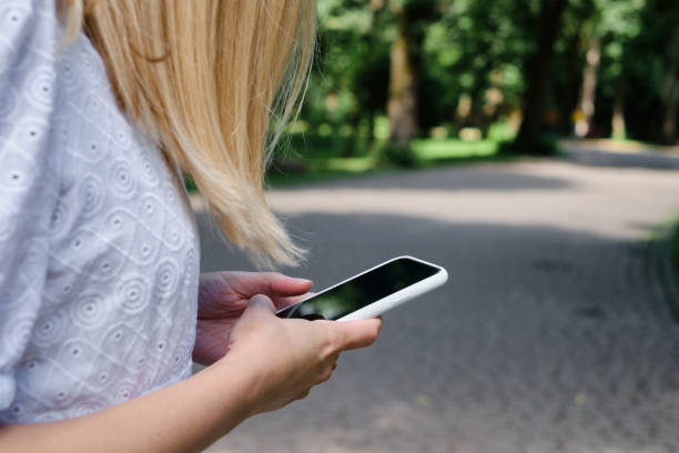 istock A girl on the street is holding a modern smartphone, sending a text message or using an application on her mobile phone. View city map using smartphone. Smartphone close-up 1336059309