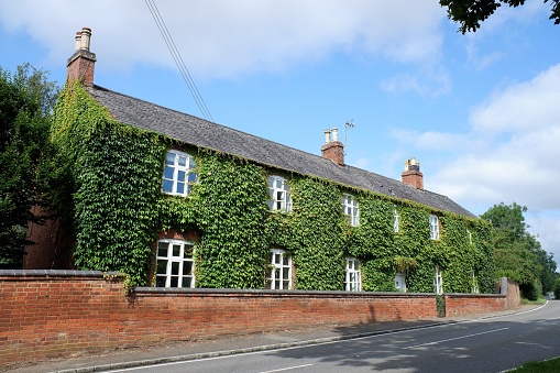 Church Langton, Market Harborough, Leicestershire, England, UK - August 23rd 2021: Farmhouse covered with ivy in Melton Road, Church Langton