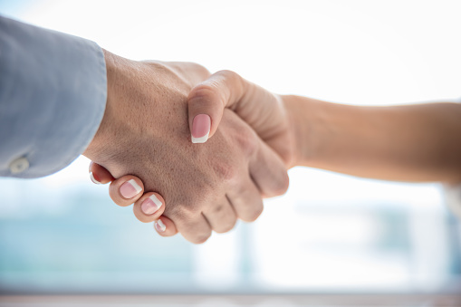 Close-up on handshake, manicured female hand gripping tight male hand, formalwear, indoors at daytime