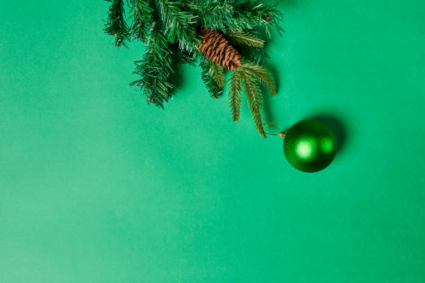 Branches of spruce tree with pine cones and Christmas toy decorations on green background. Christmas background with copy space. Xmas bauble and branches