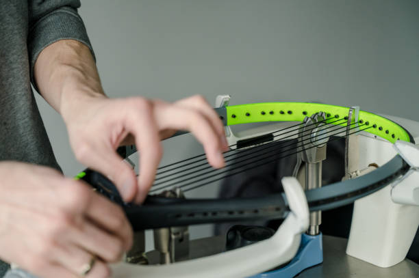 close-up de raquete de tênis em máquina de cordas eletrônica. processo de substituição de corda intestinal sintética antes do jogo. mãos de stringer fora de foco. - racket string - fotografias e filmes do acervo