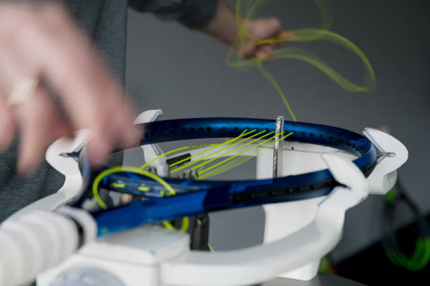 close-up de raquete de tênis em máquina de cordas eletrônica. processo de substituição de corda intestinal sintética antes do jogo. mãos de corda em movimento. - racket string - fotografias e filmes do acervo