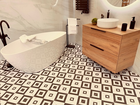 Interior of a modern bathroom. White tiles with black and white flooring and bathtub
