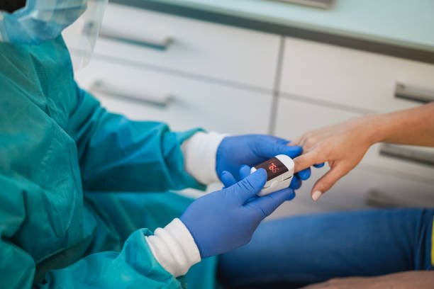 médecin examinant un patient avec un oxymètre de pouls du bout des doigts à l’intérieur de l’hôpital de laboratoire - focus sur le dispositif de maintien de la main - couleur saturée photos et images de collection