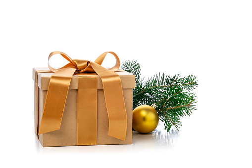 Front view of a square shaped Christmas gift box wrapped with brown craft paper shot on white background. The gift box is tied up with a golden bow. Predominant colors are brown and white.