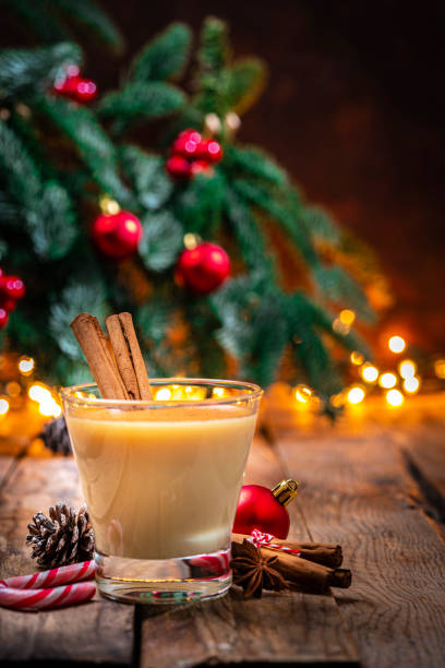 vidro eggnog na mesa de natal com árvore e luzes - cream liqueur - fotografias e filmes do acervo