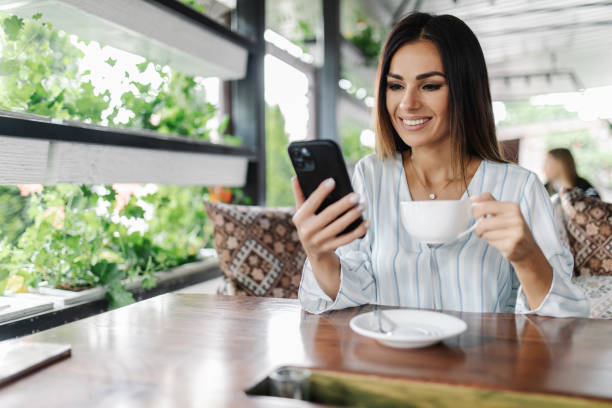 istock Young Caucasian female reading text message on her mobile phone while sitting in modern coffee shop 1336075201