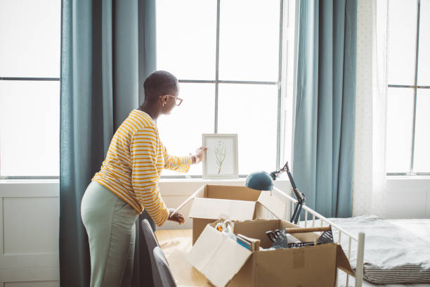 College student moving in dorm Young woman moving in college dorm. She is  caring box with stuff and organizing it in room . dorm room photos stock pictures, royalty-free photos & images