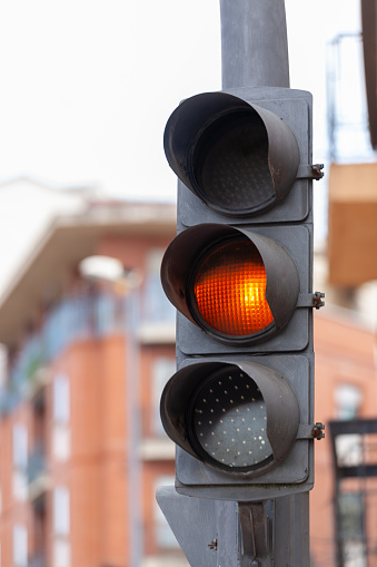 A three-light traffic light with the orange light on, a caution sign.