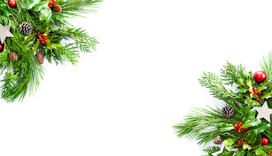 Christmas background with green fir tree branches, mistletoe and red baubles decoration on white. The composition is at the right and left of an horizontal frame leaving useful copy space for text and/or logo.
