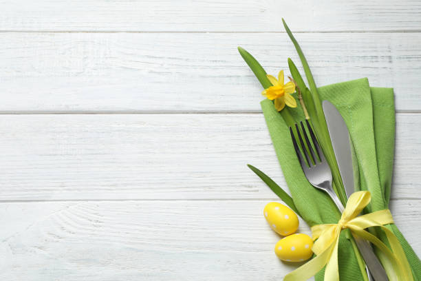 istock Cutlery set and beautiful narcissus on white wooden table, top view with space for text. Easter celebration 1336079719