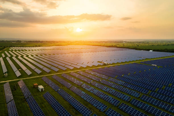 aerial view of large sustainable electrical power plant with many rows of solar photovoltaic panels for producing clean ecological electric energy in evening. renewable electricity with zero emission concept. - solar energy imagens e fotografias de stock