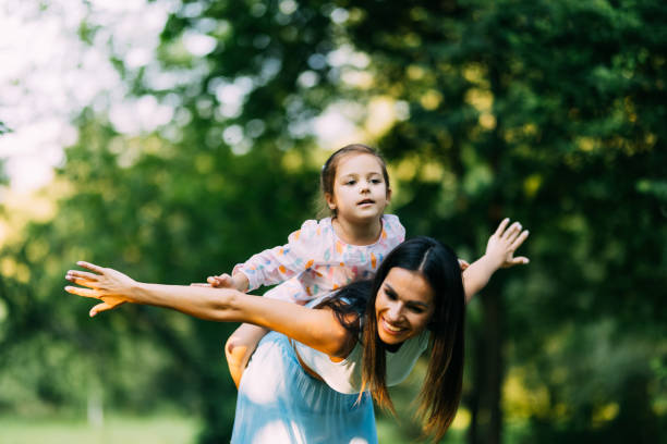 istock Young Mother Giving Daughter Ride On Back In Park 1336084140