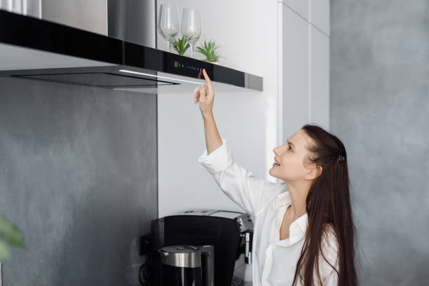 黒い調理排気を使用して若い幸せな女性の主婦 - range hood ストックフォトと画像