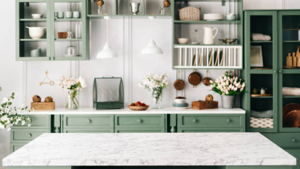 Countertop with green vintage kitchen furniture in blurred background Clean and empty marble countertop, green vintage kitchen furniture with lots of flowers and bowl of strawberries, pair of white hanging pendant lights, various crockery in blurred background kitchen stock pictures, royalty-free photos & images