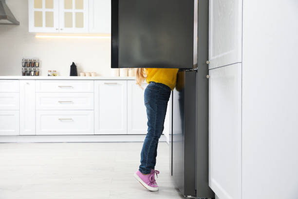 istock Little girl looking into open refrigerator in kitchen. Space for text 1336086079