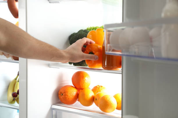istock Young man taking bell pepper out of refrigerator, closeup 1336086640