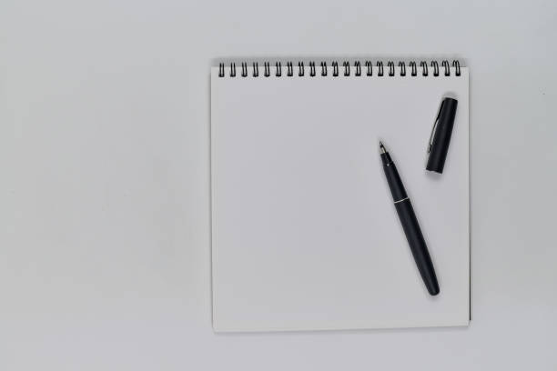 istock Flat lay photo, blank sheet of blank note and pen on white background 1336086660