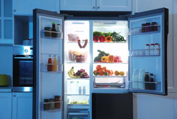 istock Open refrigerator filled with food in kitchen at night 1336087585
