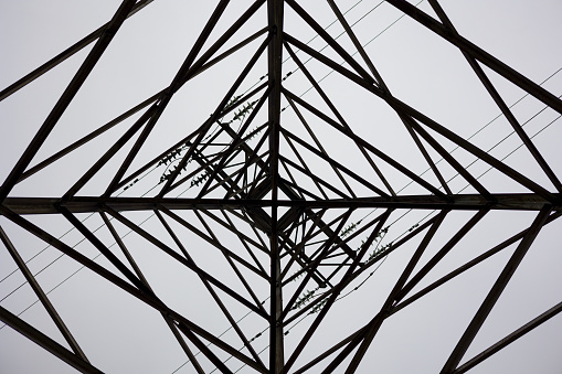 Directly Below Of Electricity Pylon Against Sky. Abstract pattern from bottom view of high voltage pole
