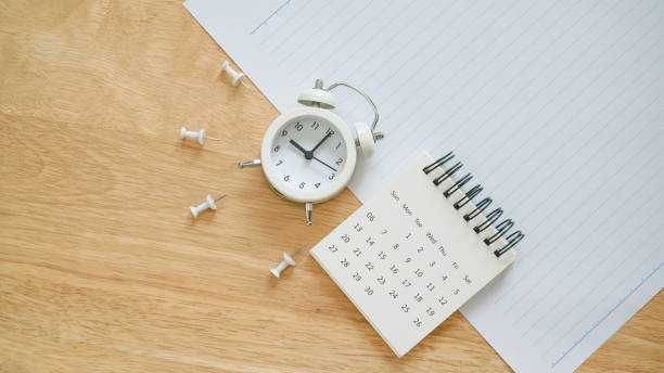 calendrier blanc, pouce et réveil analogique sur papier scolaire avec ligne sur bureau en bois pour le concept de rentrée - precise timing photos et images de collection