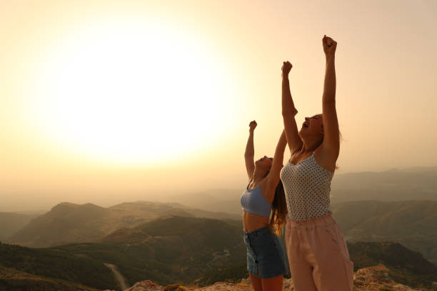 istock Two friends raising arms celebrating at sunset 1336092890
