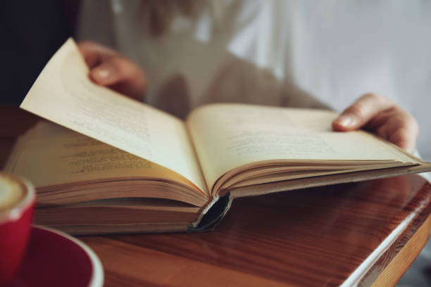 istock Woman reading book at table indoors, closeup 1336099414