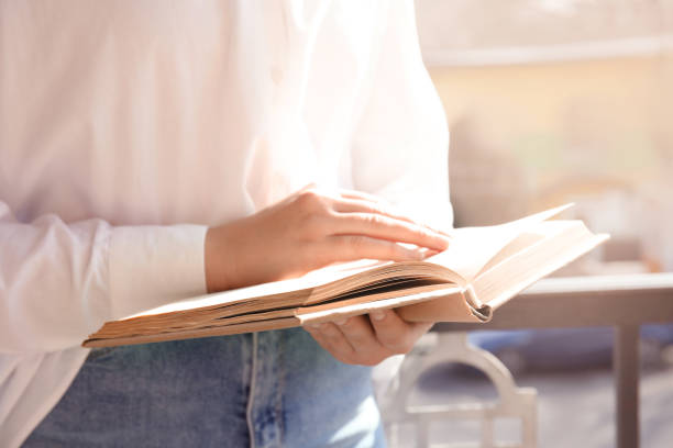 istock Woman reading book outdoors on sunny day, closeup 1336099546