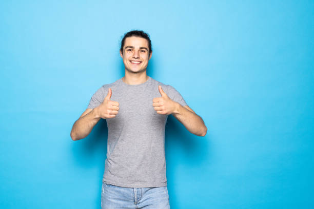 istock Young handsome man over blue background success sign doing positive gesture with hand, thumbs up smiling and happy. Cheerful expression and winner 1336100090