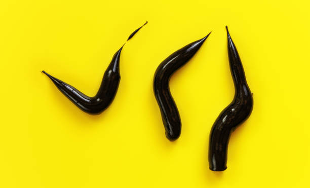 istock Three thick black cream smears charcoal toothpaste on yellow background, view from above 1336102351