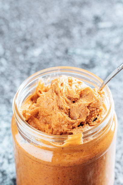 istock Spoon dipping into a glass jar with crunchy peanut butter. 1336103358