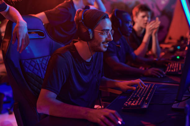 istock Smiling young professional gamer in hat and eyeglasses using computer while participating in esports tournament 1336104238