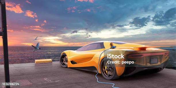 Yellow Electric Sports Car Charging From Cable On Parking Spot Overlooking Sea At Dawn Stock Photo - Download Image Now