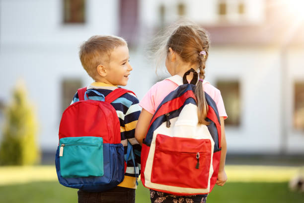 Children with backpacks going to the school stock photo