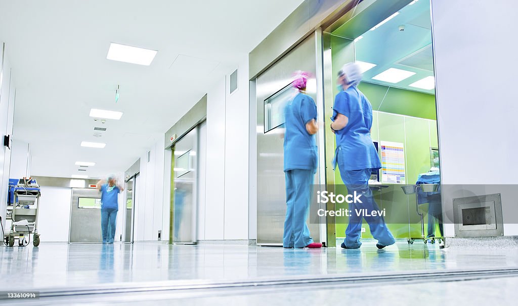 Surgeons talk in a hospital corridor blurred figures wearing medical uniforms in hospital surgery corridor Hospital Stock Photo