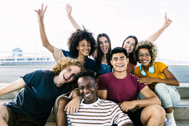 Portrait of diverse college friends sitting on city stairs - Happy multiracial group of young people having fun and relaxing in the street - Friendship, youth, unity and back to university concept stock photo