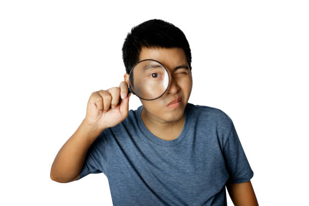 istock Young man with magnifying glass isolated on white background. 1336111273
