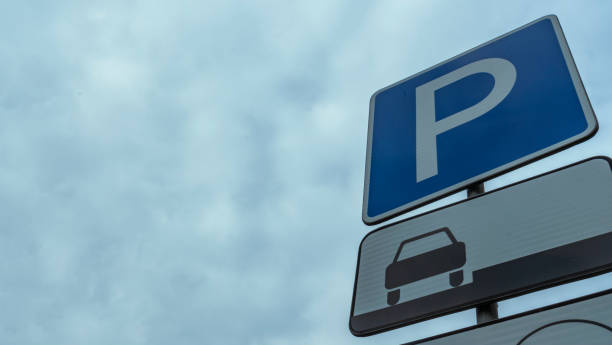 istock Blue road sign with letter P on rectangular plate isolated against a blue sky. Parking symbol on a cloudy blue sky background. Space for text. 1336113716
