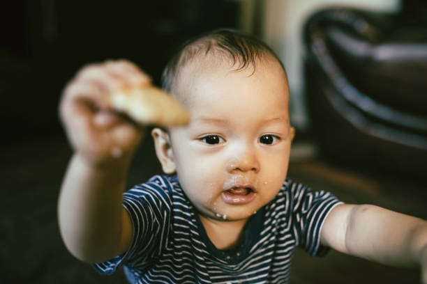 istock Baby boy  sit on floor, face covered with food, smiling 1336115399