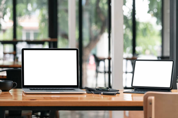 istock Mockup blank screen laptop and tablet computer on wooden table in office room. 1336115753