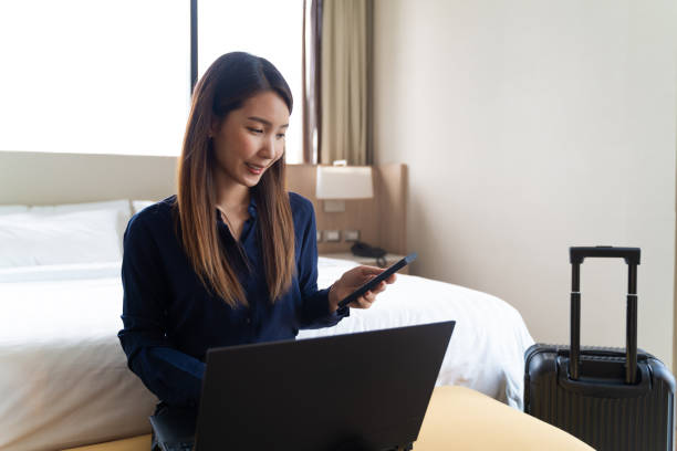Asian businesswoman using laptop working in hotel room remotely on her business travel stock photo