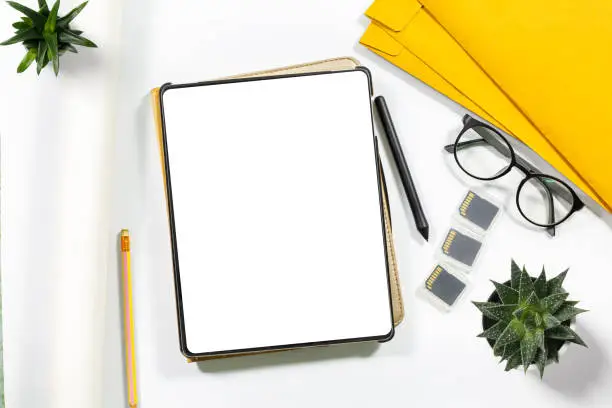 Home office workspace mockup with laptop,Overhead shot of mock up digital tablet with empty screen on whitetable. Blank screen for text message or information content.