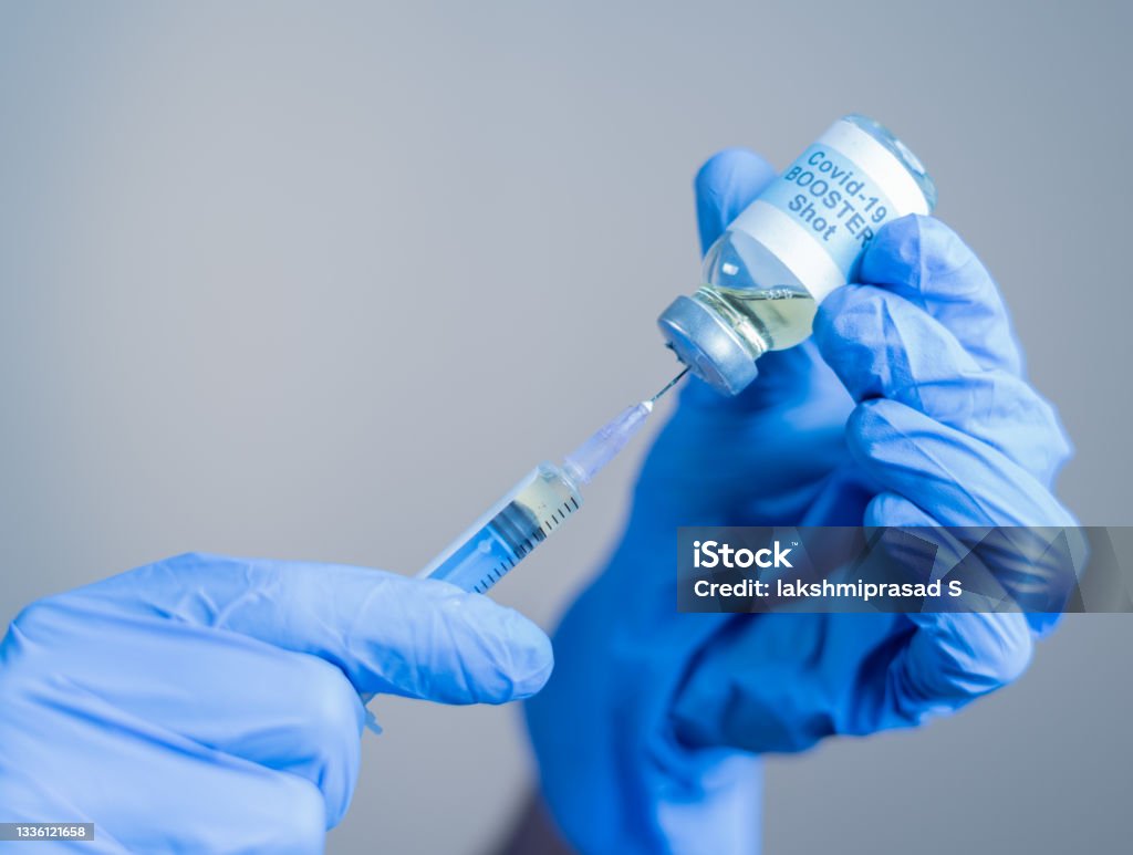 Focus on syringe, close up of doctor or nurse hands taking covid vaccination booster shot or 3rd dose from syringe Focus on syringe, close up of doctor or nurse hands taking covid vaccination booster shot or 3rd dose from syringe. Vaccination Stock Photo